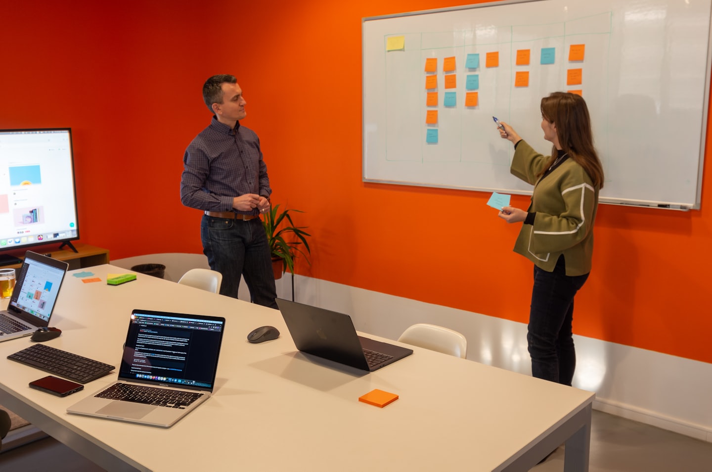 Colleagues collaborating on a whiteboard with sticky notes in an office.
